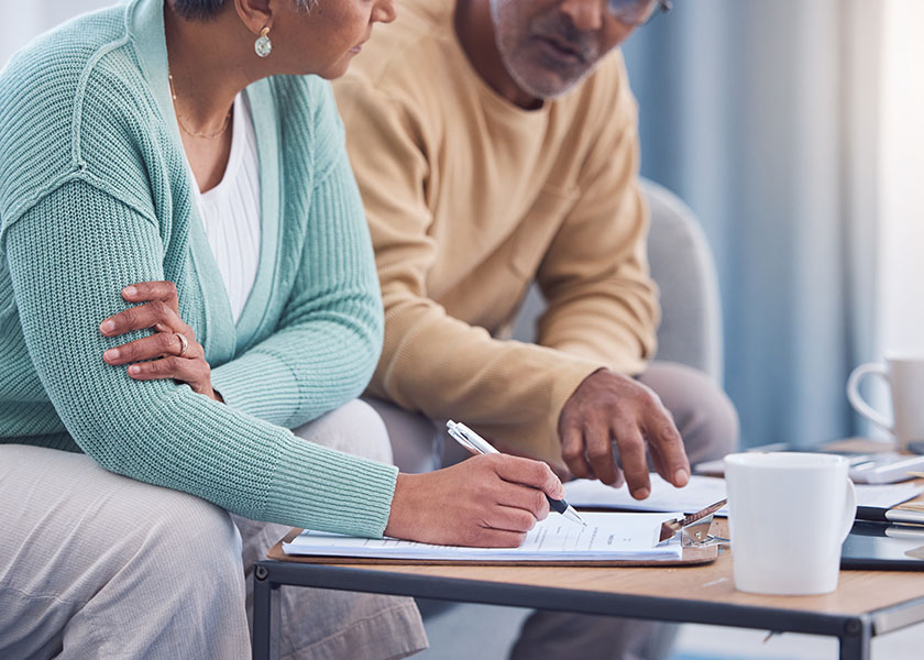 Couple seated on a couch looking over their estate plan and getting ready to sign their will.